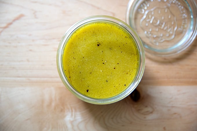 A jar of Greek salad dressing on a countertop.