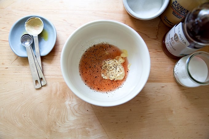 A bowl of vinegar, mustard, salt, pepper and sugar.