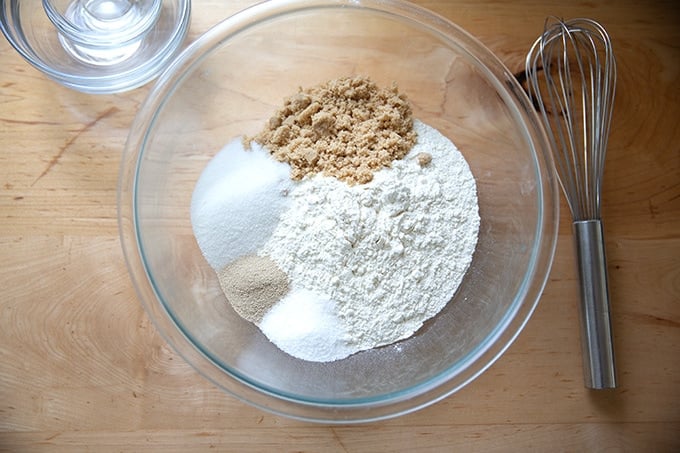 The dry ingredients to make hot cross buns in a bowl aside a whisk.