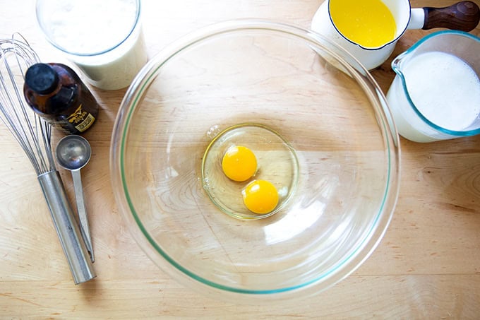 Two eggs in a large bowl aside buttermilk, melted butter, vanilla, and sourdough discard.