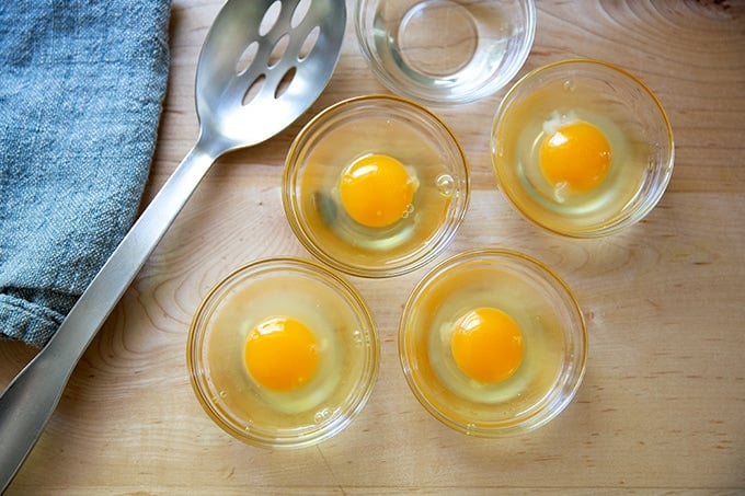 Four eggs in four small bowls.