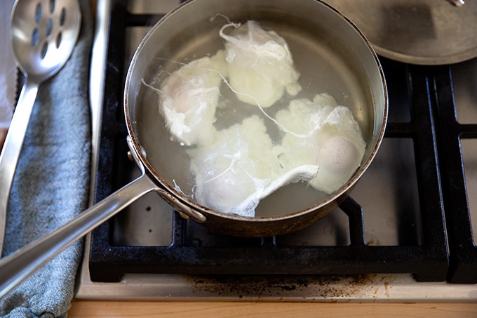 A shallow pot holding water and 4 poached eggs.