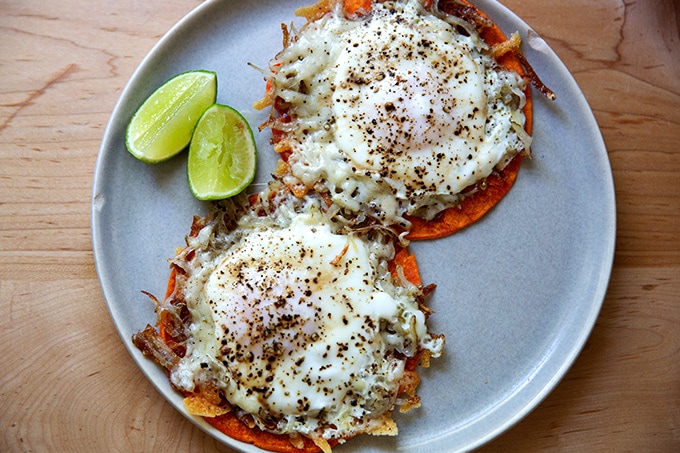 A plate of crispy potatoes, egg, and cheese on tortillas.