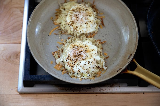 A skillet holding crispy potatoes, cheese, and eggs.