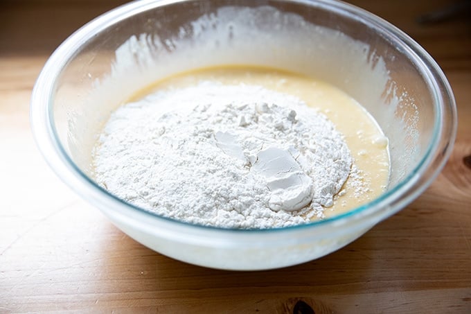 Flour added to a bowl of wet ingredients to make pound cake.