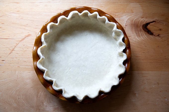 A pie plate fitted with pie dough, its edges crimped. - 9