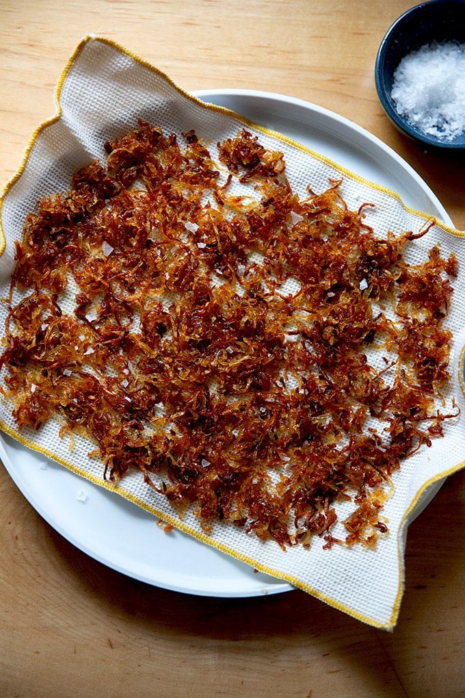 A plate lined with a cloth towel and crispy fried shallots on top.