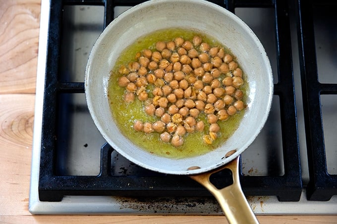A small skilled of chickpeas frying in olive oil.