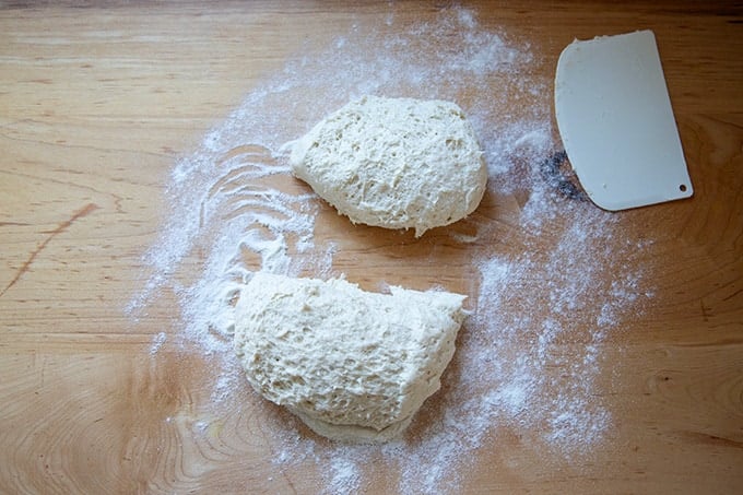 Gluten-free pizza dough, risen, and cut in half on a countertop.