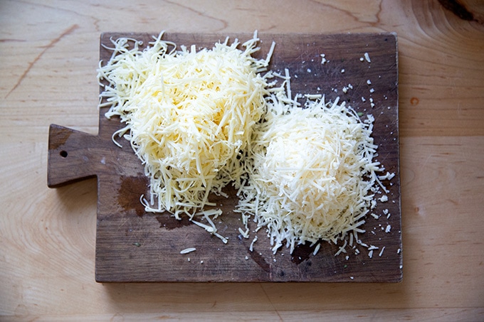 Two piles of grated cheese on a board.