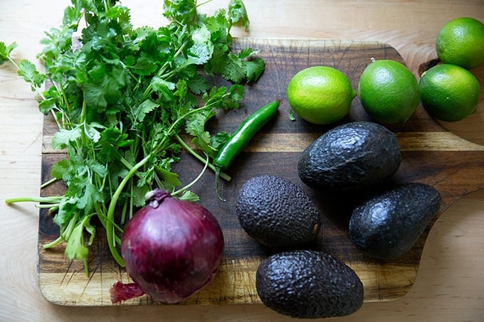 A board with the ingredients to make guacamole on it.