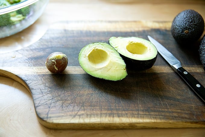 A halved avocado on a board.