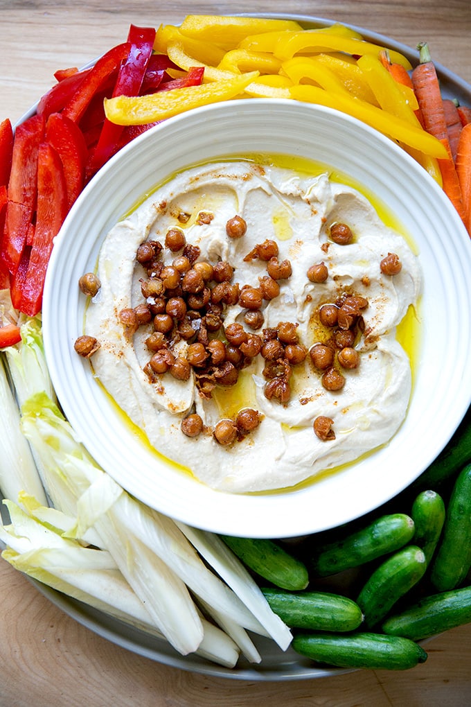 A platter of homemade hummus surrounded by veggies.