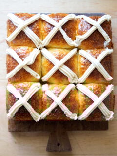 Nine hot cross buns on a serving board.