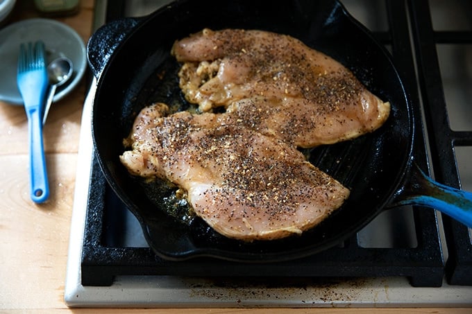 Chicken breasts grilling on a grill pan stovetop.