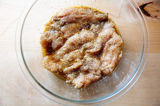 Chicken breasts marinating in a large bowl.