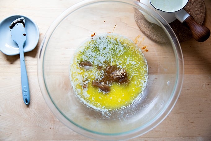 A bowl of melted butter, brown sugar, molasses, maple syrup and salt, unmixed.