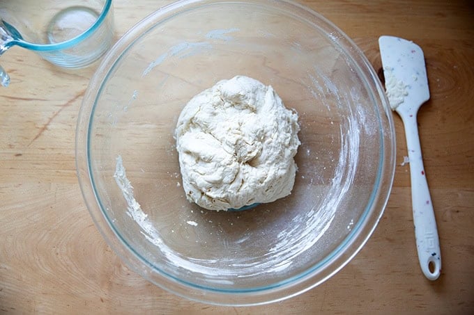A mixed ball of dough in a large glass bowl.