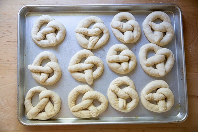 Unbaked soft pretzels on an oiled sheet pan.