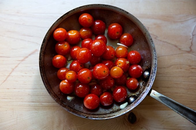 A skillet with cherry tomatoes coated in olive oil. 