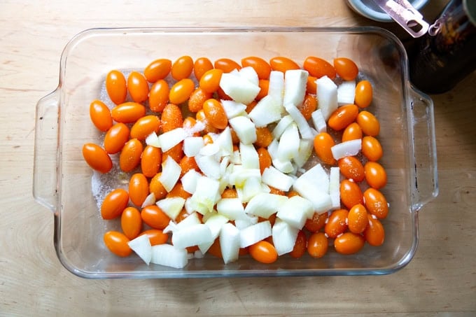 A 9x13-inch pan filled with yellow cherry tomatoes, onions, olive oil and salt.