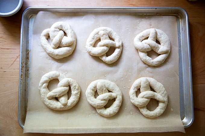 Unbaked soft pretzels on a sheet pan.
