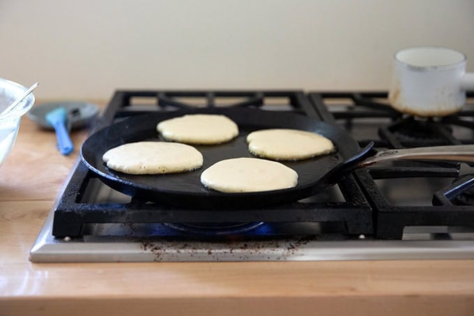 Sourdough discard pancakes cooking in a skillet.