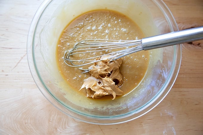 A large bowl with peanut butter cookie dough being mixed with a whisk.