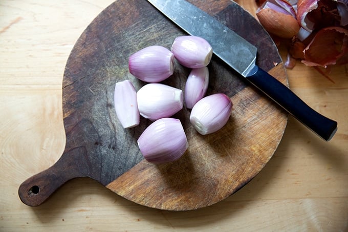 Peeled shallots on a cutting board.