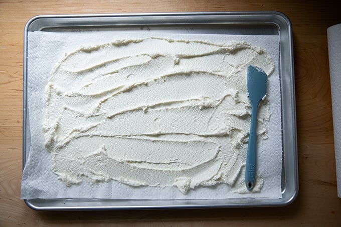 Ricotta spread across a paper-towel-lined sheet pan.