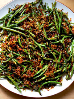 A platter of roasted green beans with crispy fried shallots.