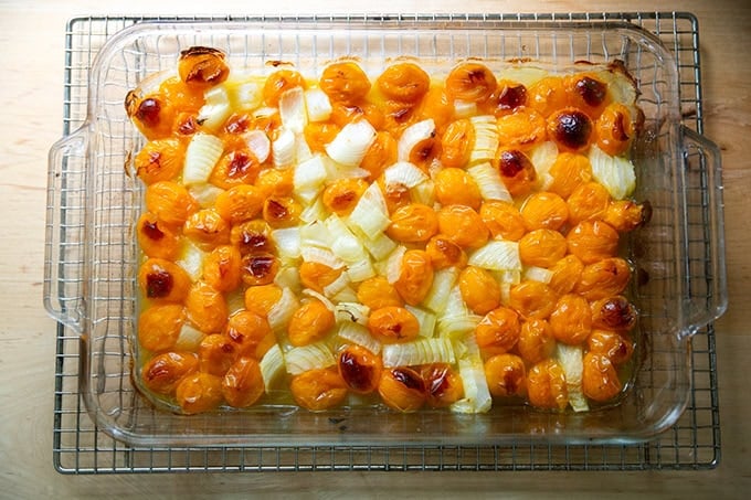 A 9x13-inch pan filled with roasted yellow cherry tomatoes and onions.