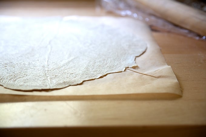 Rolled out sourdough cracker dough on a sheet of parchment paper.