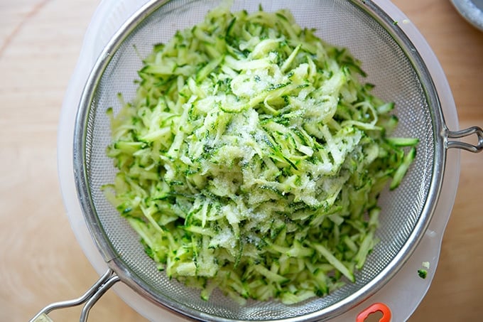 Shredded zucchini, salted, in a colander.