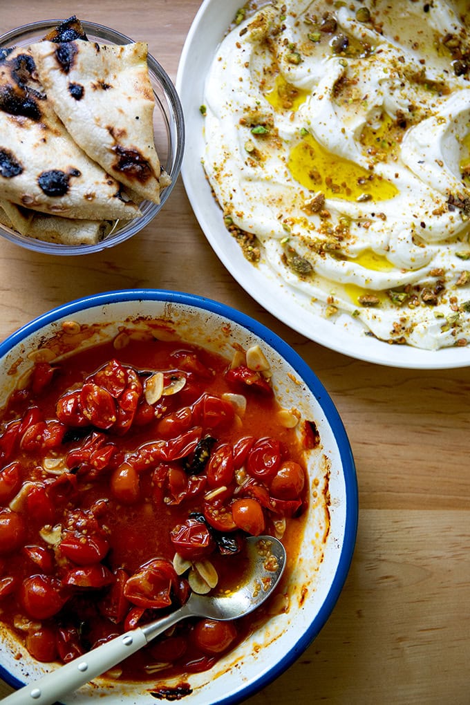 Two platters: roasted tomatoes and whipped ricotta aside charred bread.