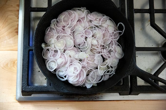 Shallots in a cast iron skillet on the stovetop.