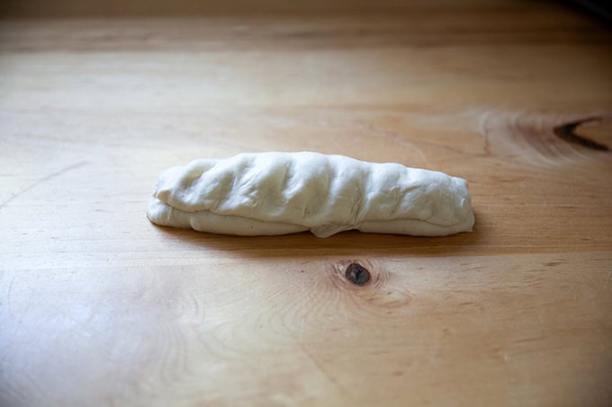 An unbaked baguette in the process of being shaped.