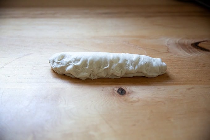 An unbaked baguette in the process of being shaped.