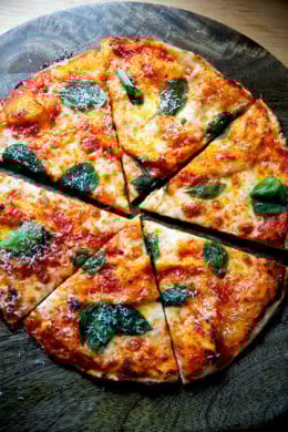 A cut gluten-free Margherita pizza on a cutting board.