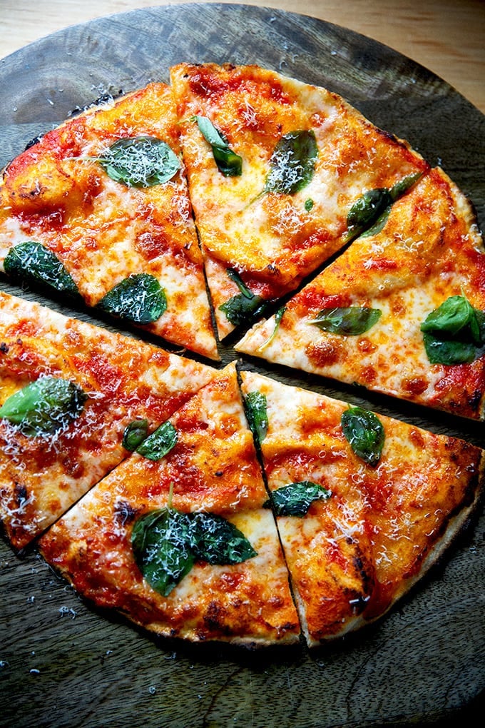 A cut gluten-free Margherita pizza on a cutting board.