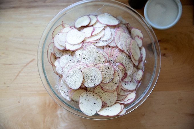 A large bowl filled with sliced potatoes.