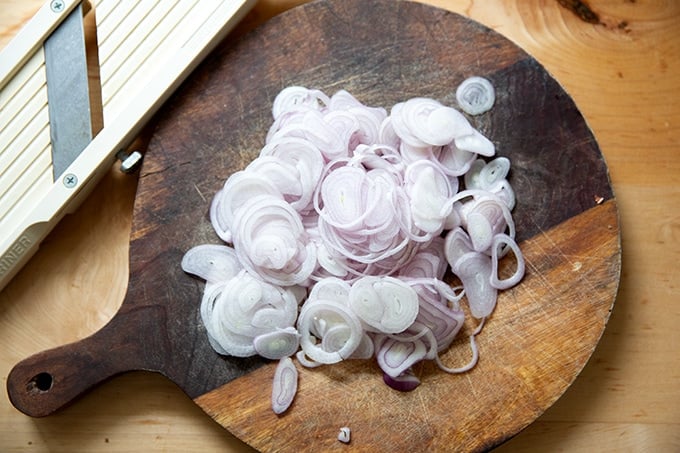 Sliced shallots on a cutting board.
