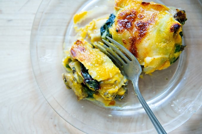 A slice of butternut squash lasagna with greens and mushrooms.