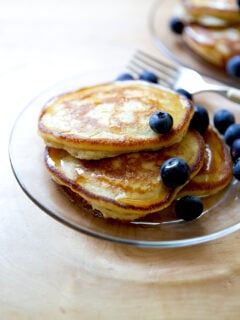 A plate of sourdough discard pancakes topped with syrup and blueberries.