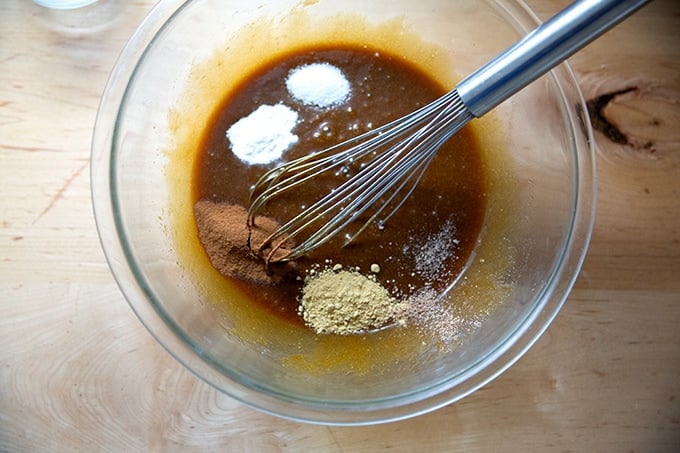 A bowl of brown sugar, white sugar, molasses, butter, egg, and spices.