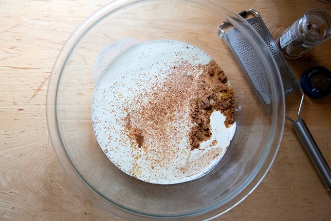 A large bowl filled with heavy cream, eggs, sugar, salt and spices for roasted butternut squash pie. - 8
