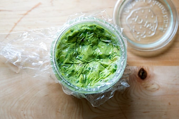 A jar of guacamole, sealed with plastic wrap for storage.