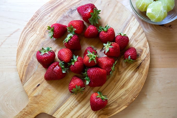 A cutting board topped with strawberries.