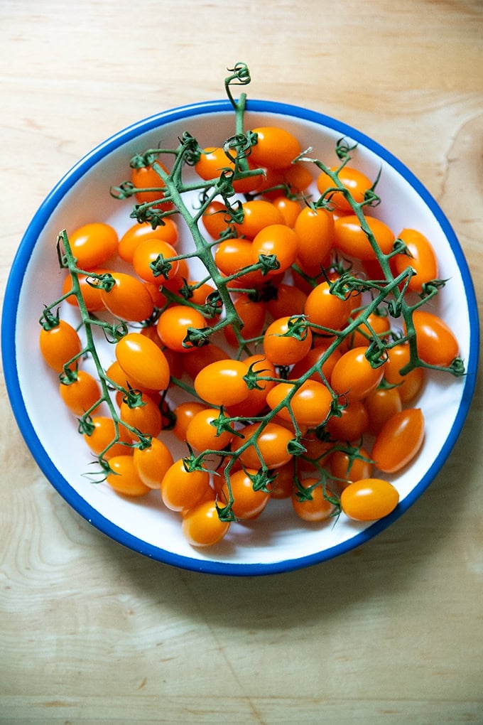 A plate of yellow cherry tomatoes on the vine.