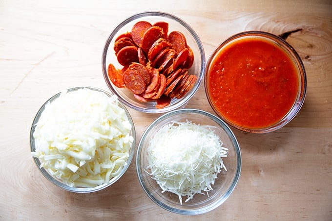 Bowls of toppings for Sicilian-style pizza: cheese, sauce, and pepperoni.